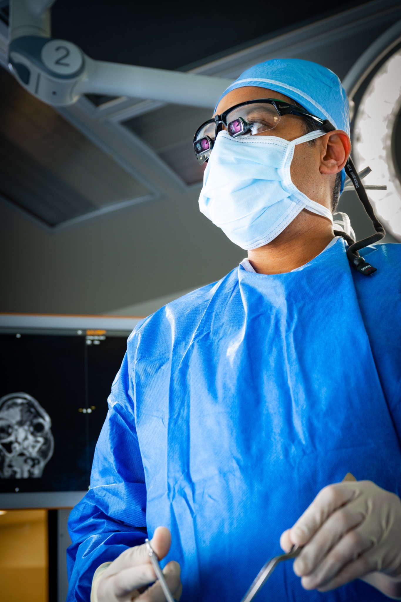 Dr. Patel in surgical attire wearing magnifying loupes in the operating room